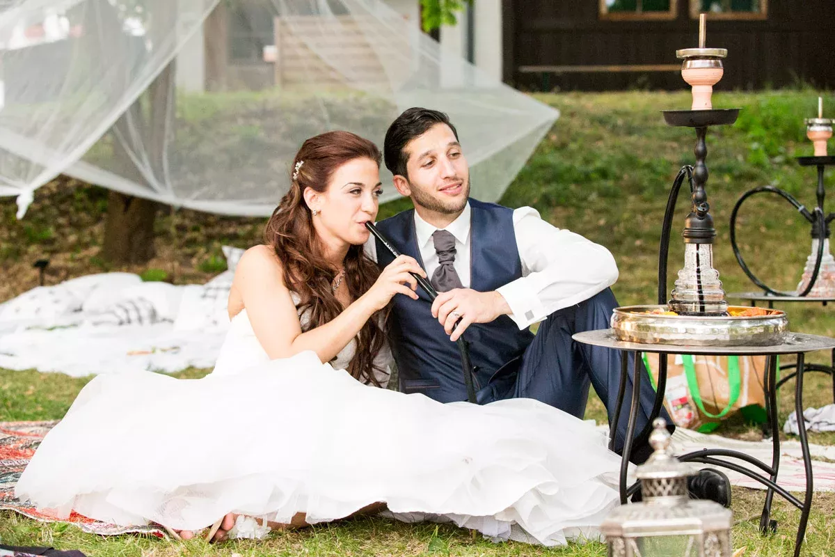 Hochzeitsfotos Schloss Diedersdorf – Braut und Bräutigam genießen eine Shisha-Pause während der Feier.