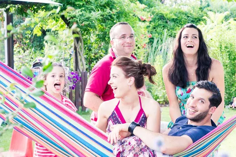 Engagement Shooting: Familie lacht und genießt fröhliche Zeit im Garten mit Hängematte