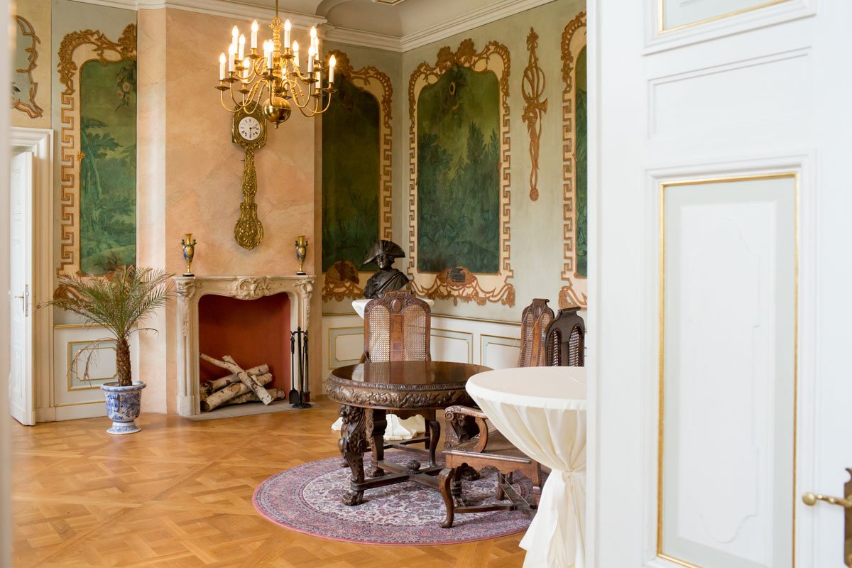 Historischer Salon im Schloss Friedrichsfelde mit kunstvollen Wandgemälden und antiken Möbeln, ideal für eine Trauung.