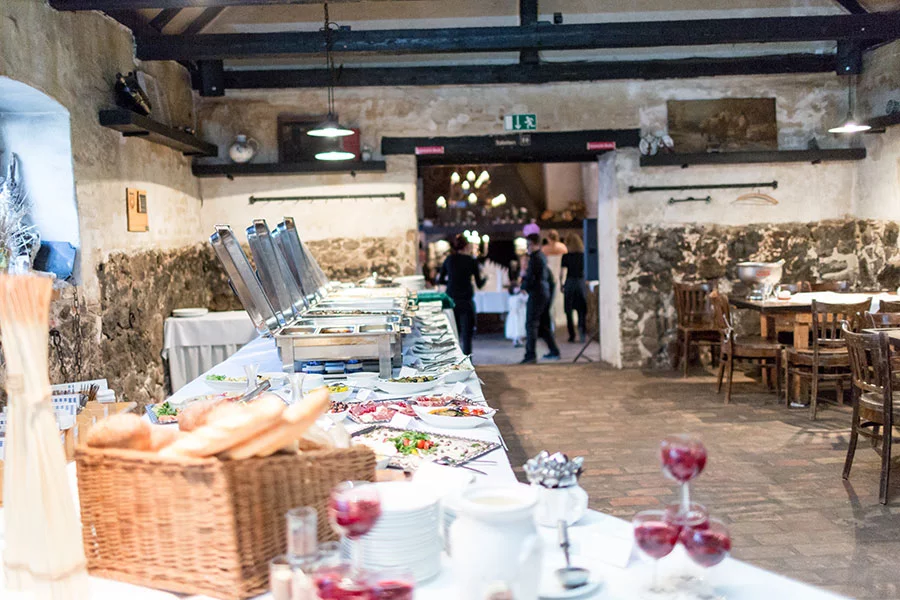 Buffet in einem rustikalen Saal im Schloss Diedersdorf, dekoriert für eine Hochzeitsfeier, mit einer Auswahl an Speisen und Getränken.