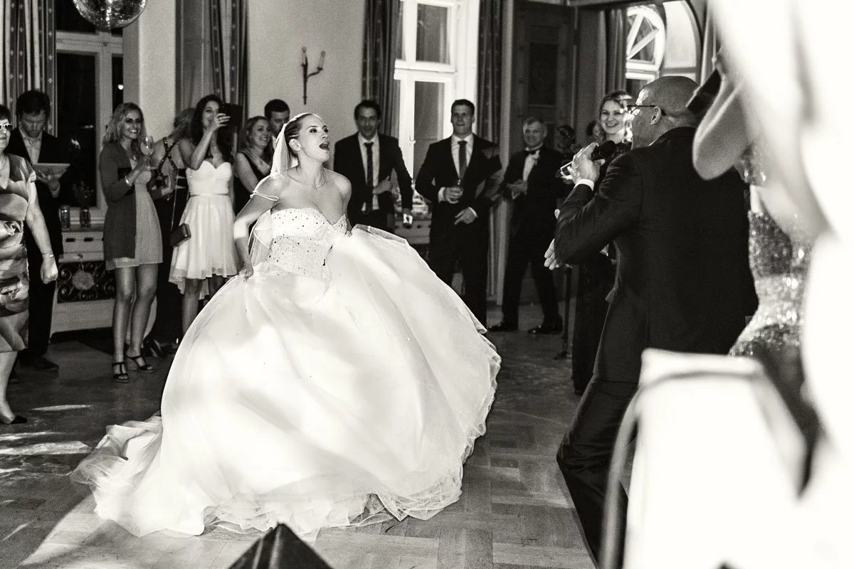 Braut tanzt begeistert mit der Hochzeitsband, umgeben von applaudierenden Gästen.