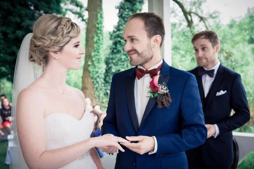 Brautpaar beim Ringtausch während der Hochzeit an der Seelodge Kremmen, begleitet von einem Trauzeugen.