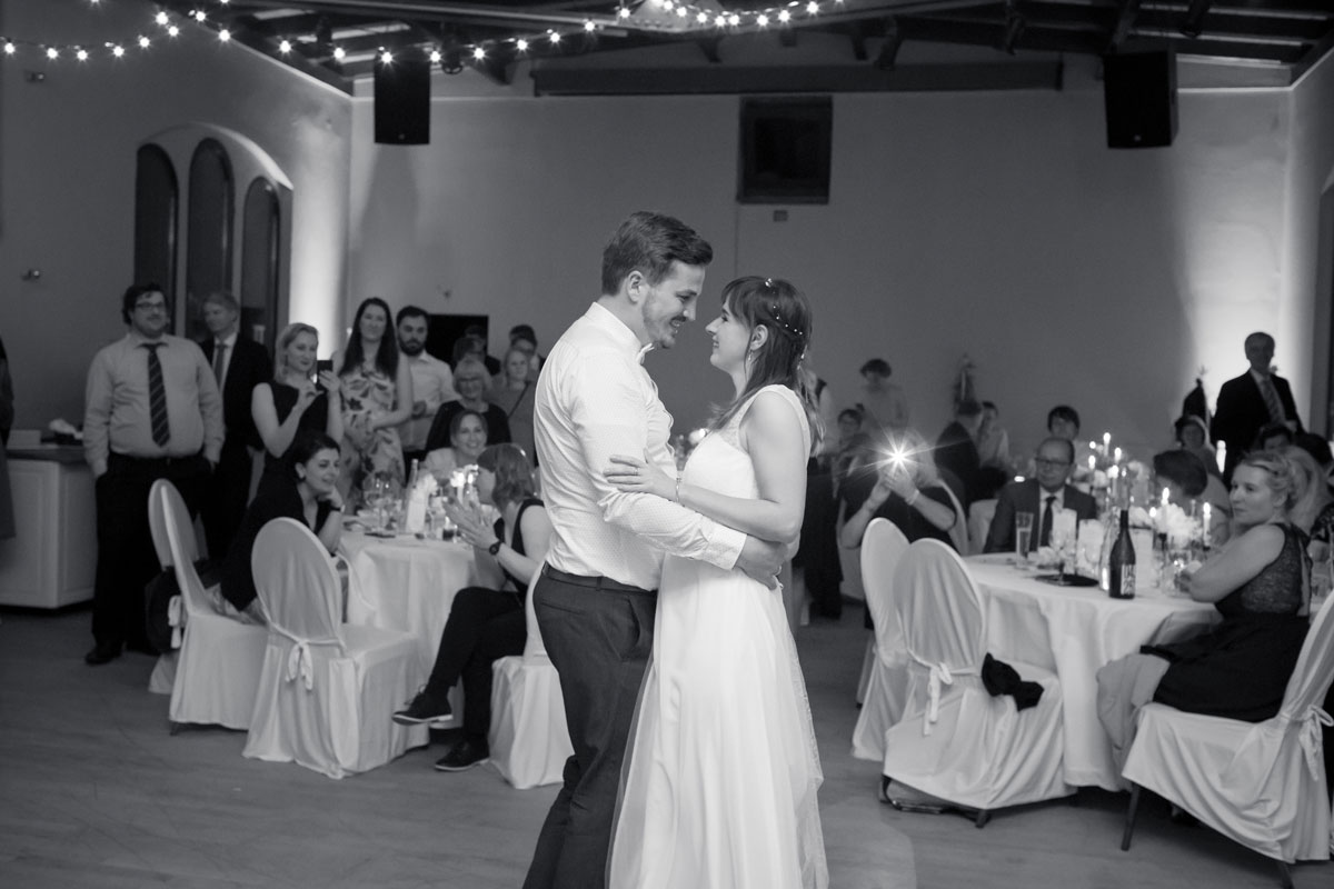 Hochzeit Villa Kreuzberg- Braut und Bräutigam tanzen ihren ersten Tanz in einem festlich dekorierten Saal, umgeben von applaudierenden Gästen.