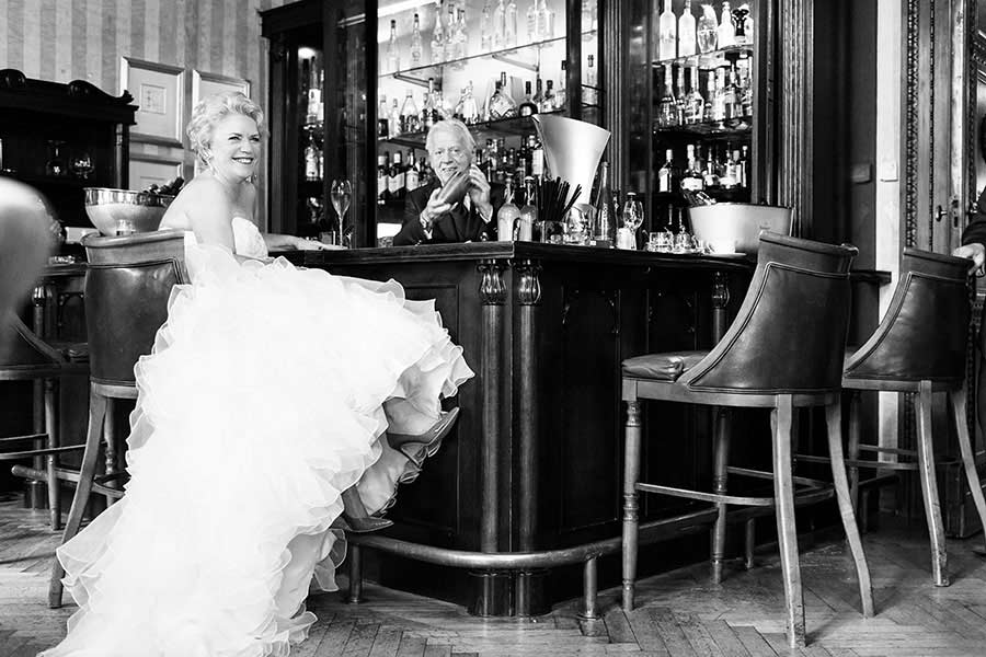 Brautpaar an der Bar im Schlosshotel Grunewald, die Braut lacht herzlich, während der Bräutigam sie zufrieden ansieht.