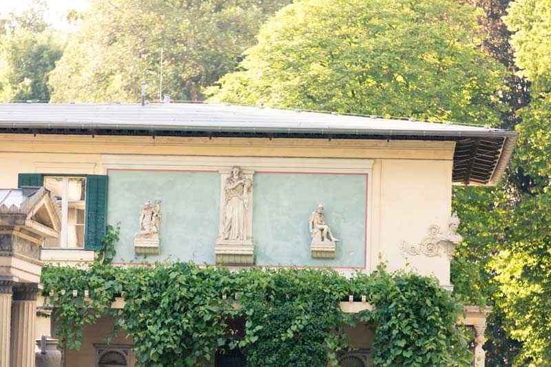 Detailansicht des Schlosses Glienicke mit kunstvollen Statuen und umgeben von üppigem Grün.