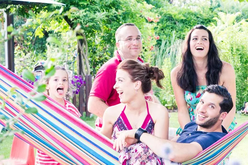 Engagement Shooting: Familie lacht und genießt fröhliche Zeit im Garten mit Hängematte