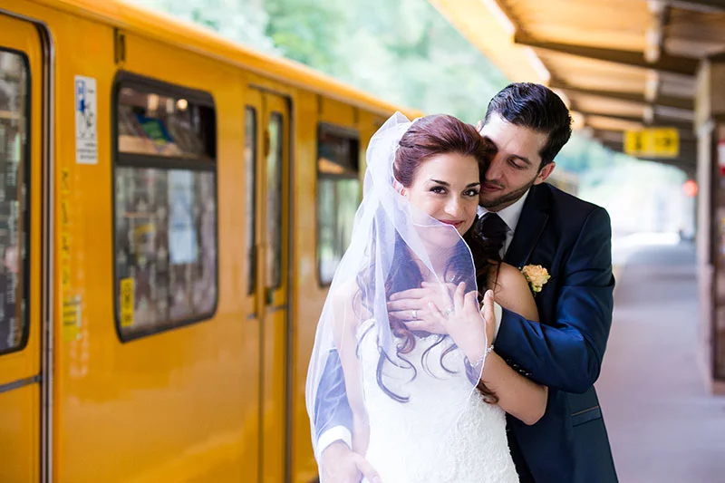 Brautpaar vor einer Berliner U-Bahn während ihrer Hochzeit, fotografiert von einem Hochzeitsfotografen in Berlin.
