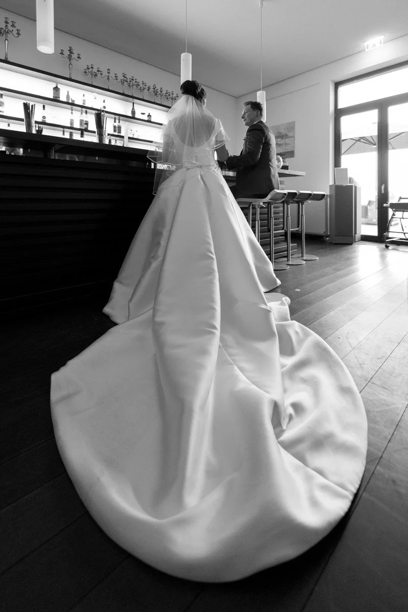 Hochzeitsfotos SeePavillon am Tegeler See – Die Schleppe des Brautkleids breitet sich über den Boden aus, aus einer ungewöhnlichen Perspektive eingefangen.